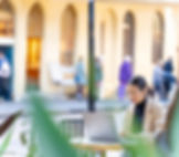 Young woman sitting at an outdoor table on a laptop